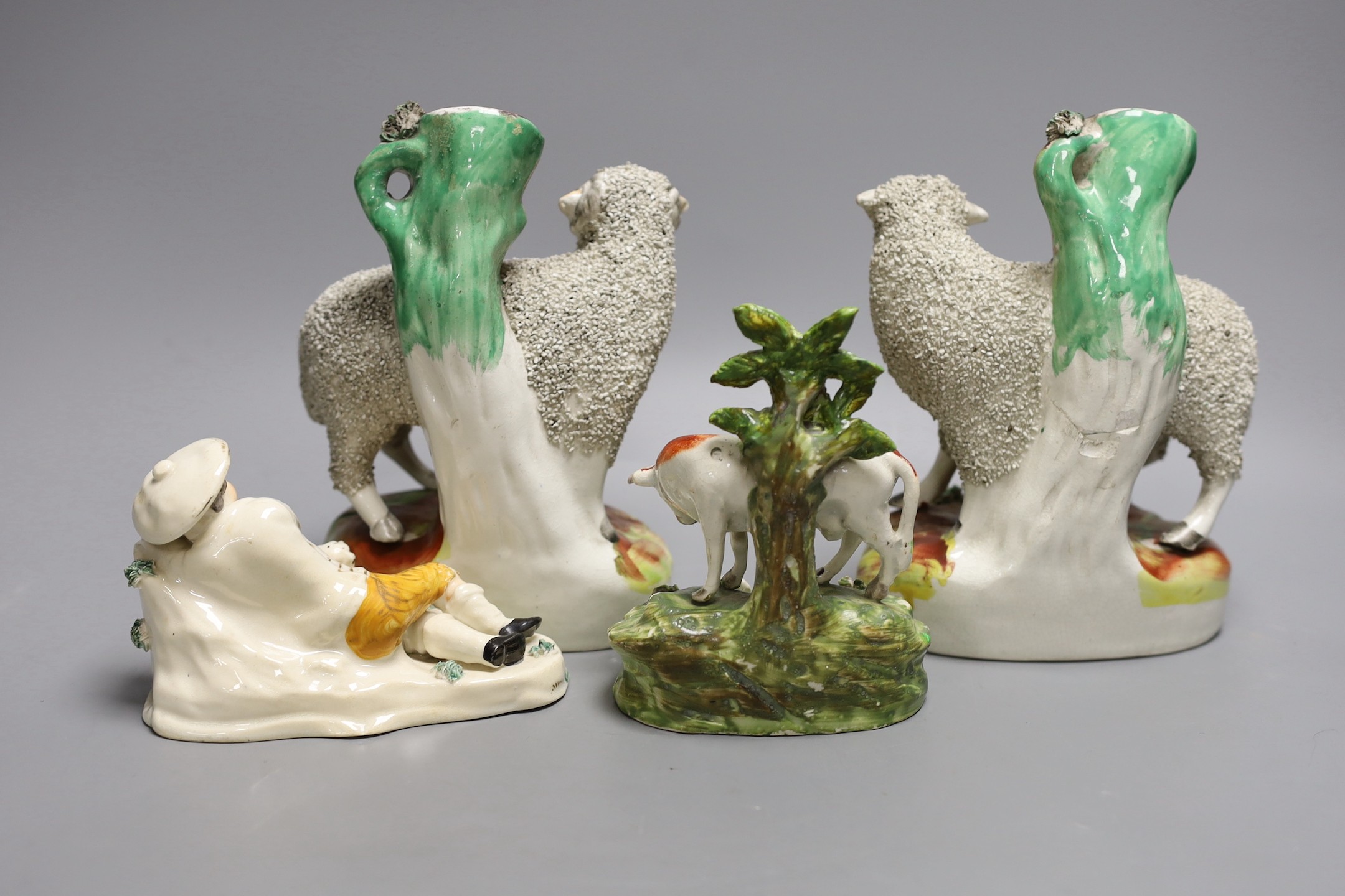 A pair of Staffordshire sheep spill vases, 19 cm high, a similar cow group and a recumbent man and dog